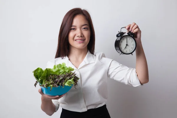 Ung asiatisk kvinna med klocka och sallad. — Stockfoto