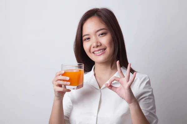 Mladá asijská žena pít pomerančový džus Ok nenasvědčuje. — Stock fotografie
