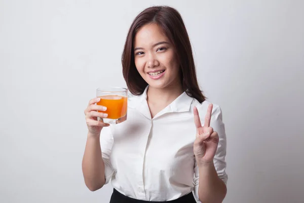 年轻的亚裔女子显示胜利的手势喝桔子汁. — 图库照片