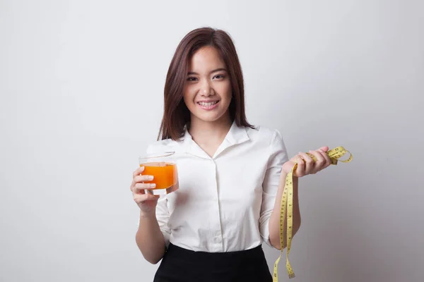 Asiatisk kvinna dricka apelsinjuice håll måttband. — Stockfoto