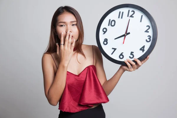 Sleepy jonge Aziatische vrouw met een klok in de ochtend. — Stockfoto