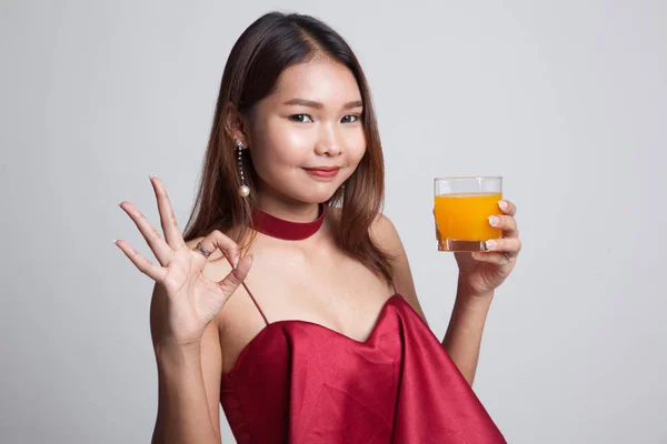 Giovane donna asiatica bere succo d'arancia spettacolo OK segno . — Foto Stock