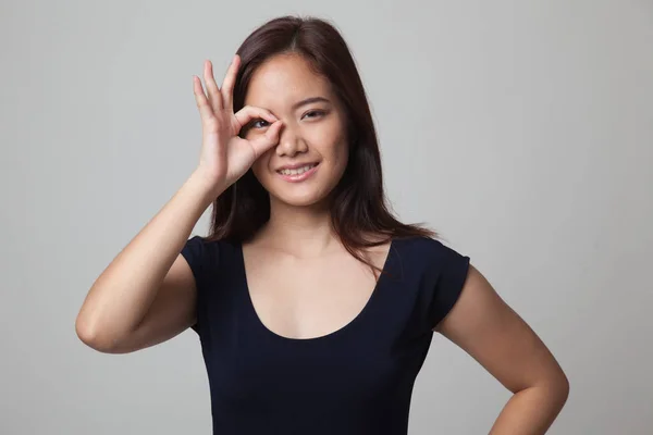 Όμορφη νεαρά γυναίκα της Ασίας δείχνουν Ok υπογράψει πάνω από το μάτι της. — Φωτογραφία Αρχείου