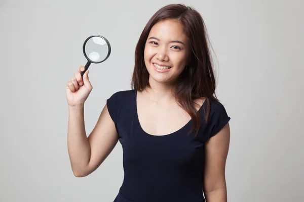 Young Asian woman with a magnifying glass. — Stock Photo, Image