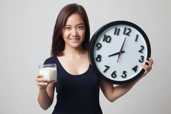 Gezonde Aziatische vrouw drinkglas van melk houd clock. — Stockfoto
