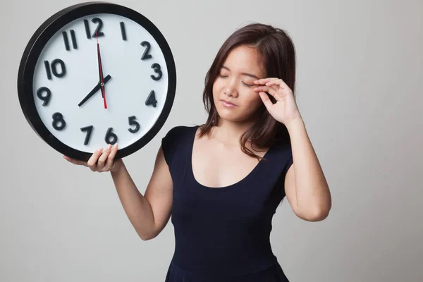 Sleepy young Asian woman with a clock in the morning. — Stock Photo, Image