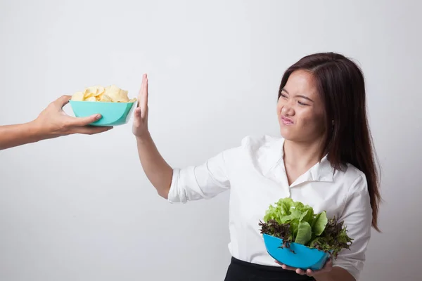 Jonge Aziatische vrouw met salade nee zeggen tegen potato chips. — Stockfoto