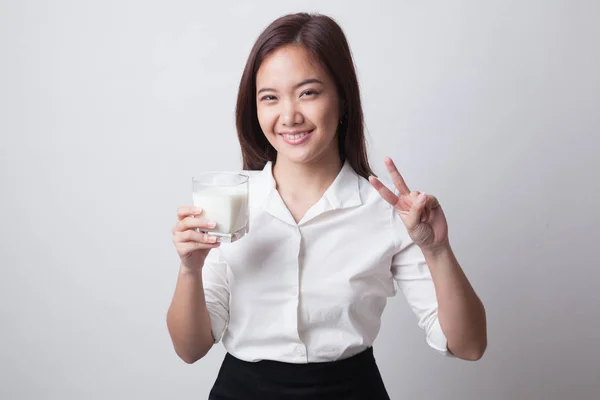 Gezonde Aziatische vrouw drinken van een glas melk overwinning teken weergeven. — Stockfoto