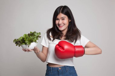 Genç Asyalı kadın boks eldiven ve salata ile.