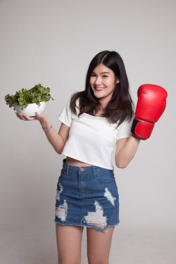 Genç Asyalı kadın boks eldiven ve salata ile.