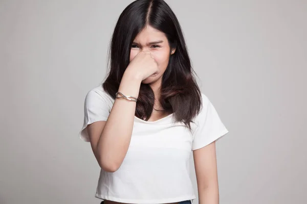 Junge asiatische Frau hält ihre Nase wegen eines schlechten Geruchs. — Stockfoto