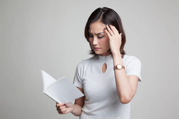 Joven asiática mujer got headache leer un libro . — Foto de Stock