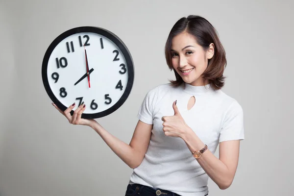 Jonge Aziatische vrouw duimen omhoog met een klok. — Stockfoto