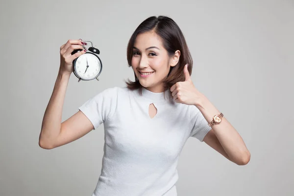 Young Asian woman show thumbs up with a clock. — Stock Photo, Image