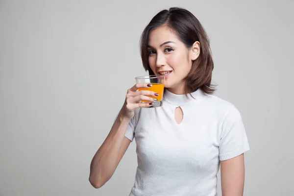 Молода азіатка п'є апельсиновий сік . — стокове фото