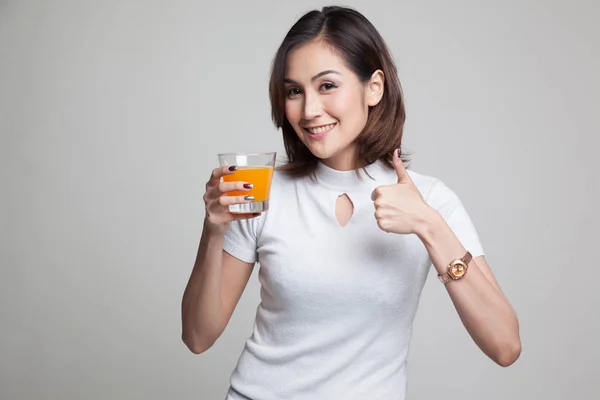 Giovane donna asiatica pollice in su bere succo d'arancia . — Foto Stock