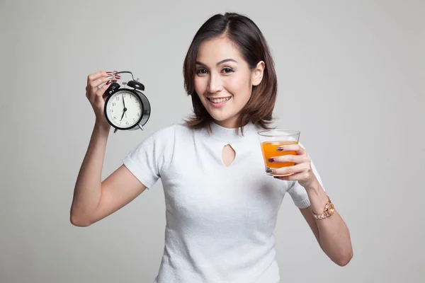 Asian woman with a clock drink orange juice. — Stock Photo, Image