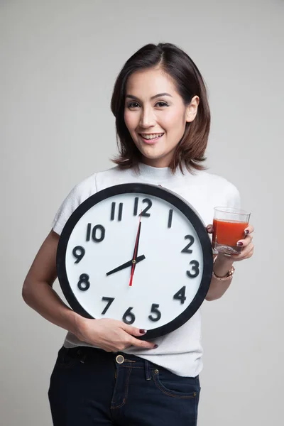 Młoda kobieta azjatyckich z soku pomidorowego i zegar. — Zdjęcie stockowe