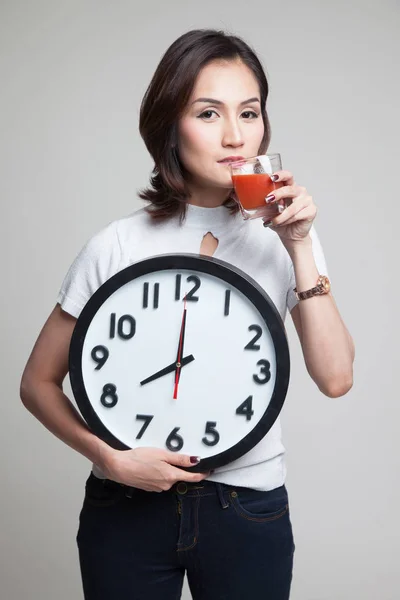Jonge Aziatische vrouw met tomatensap en klok. — Stockfoto
