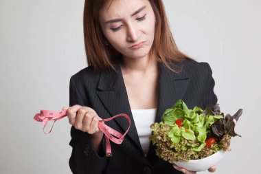 Ölçme bant ve salata ile mutsuz Asyalı kadın.
