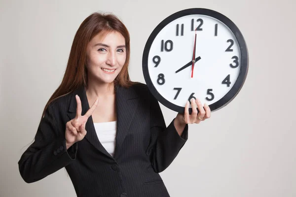 Joven mujer de negocios asiática muestra signo de victoria con un reloj . —  Fotos de Stock