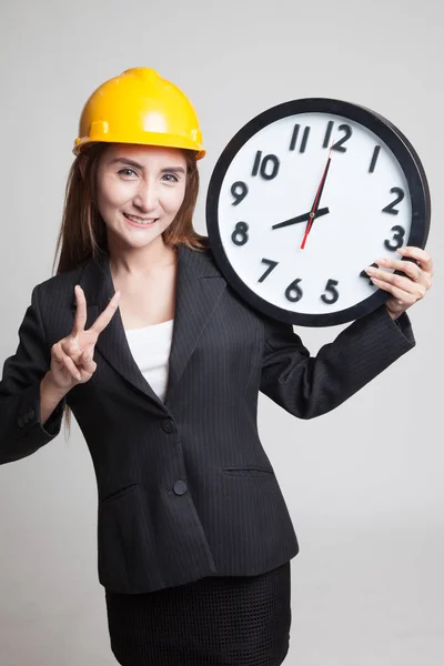 亚洲工程师女人与一个时钟显示胜利的手势. — 图库照片