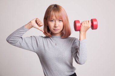 Dumbbells ile mutsuz Asyalı kadın başparmak aşağı.