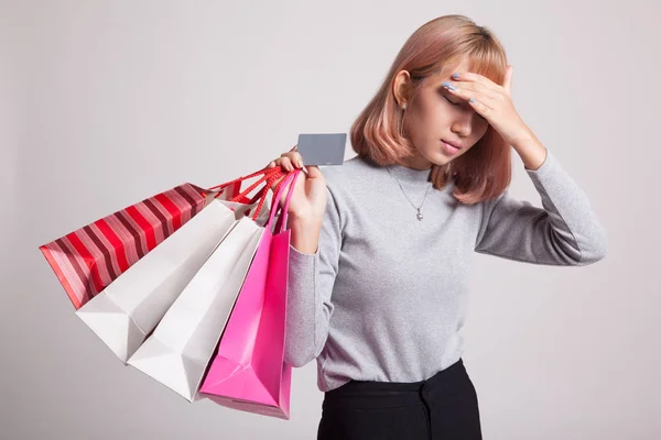 Ongelukkige jonge Aziatische vrouw met shopping tassen en credit card. — Stockfoto