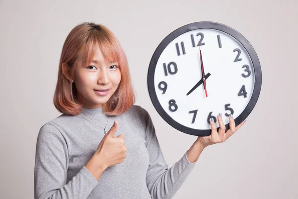 Young Asian woman thumbs up with a clock. — Stock Photo, Image