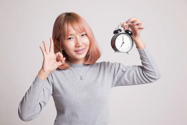 Young Asian woman show OK with a clock. — Stock Photo, Image