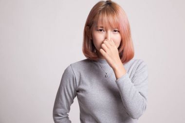 Kötü bir koku yüzünden burnunu tutan genç Asyalı kadın.