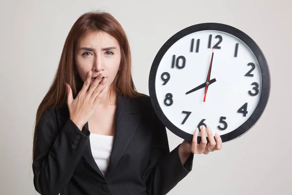 Sleepy young Asian woman with a clock in the morning. — Stock Photo, Image
