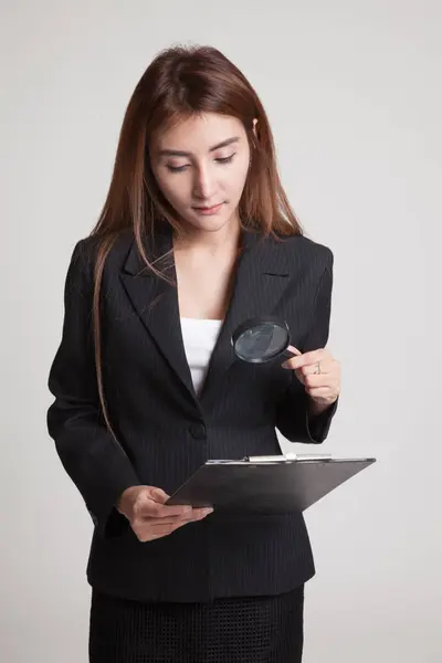 Jonge Aziatische vrouw met een chequerapport Vergrootglas. — Stockfoto