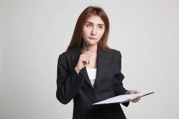 Junge asiatische Geschäftsfrau denkt mit Stift und Klemmbrett. — Stockfoto