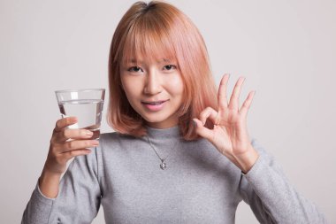 Genç Asyalı kadın göster Ok ile içme suyu bir bardak.