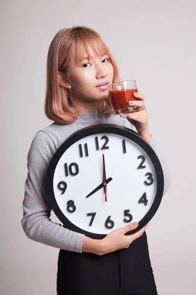 Junge asiatische Frau mit Tomatensaft und Uhr. — Stockfoto