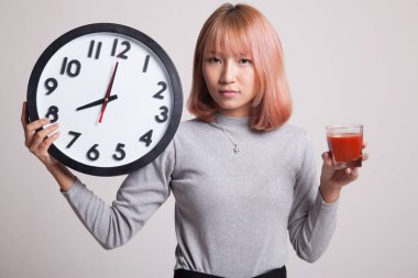 Domates suyu ve saat ile genç Asyalı kadın.