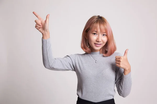Jonge Aziatische vrouw punt en duimschroef opwaarts. — Stockfoto