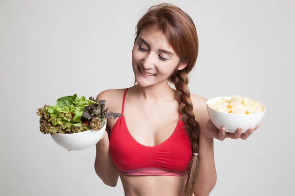 Mooie Aziatische gezond meisje salade en aardappels, chips. — Stockfoto