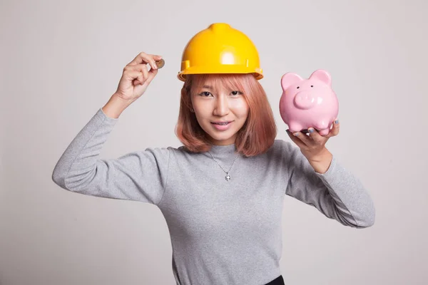 Asian engineer woman with a coin and piggy coin bank. — Stock Photo, Image