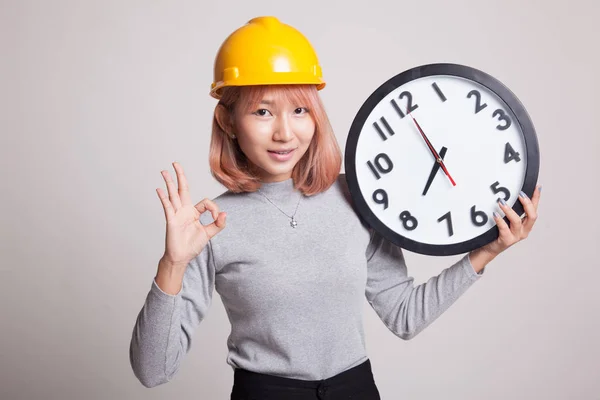 Asiatique ingénieur femme montrer OK avec une horloge . — Photo