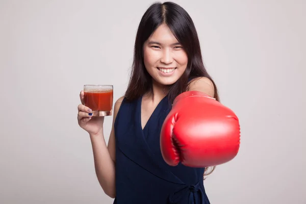 Giovane donna asiatica con succo di pomodoro e guanto da boxe . — Foto Stock