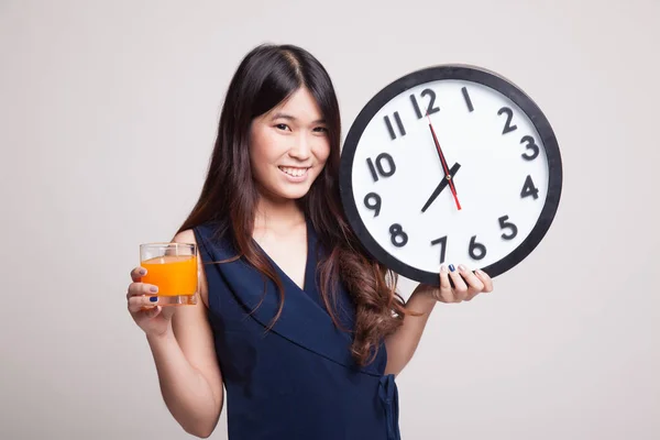 Femme asiatique avec une horloge boisson jus d'orange . — Photo