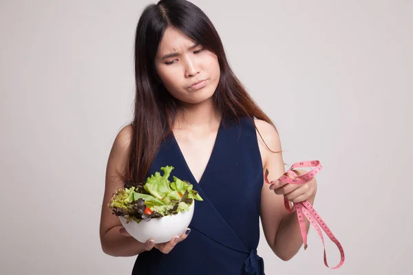 Olycklig asiatisk kvinna med mätning av tejp och sallad. — Stockfoto