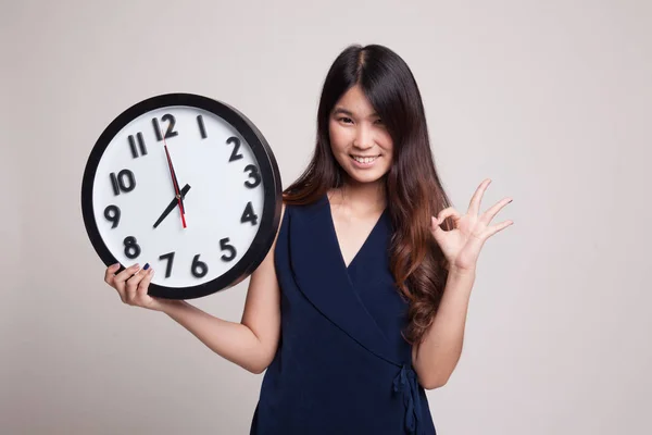 Jovem mulher asiática mostrar OK com um relógio . — Fotografia de Stock