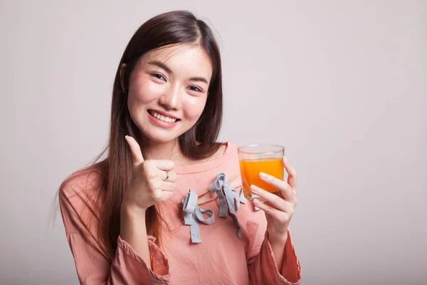 Junge asiatische Frau Daumen nach oben trinken Orangensaft. — Stockfoto