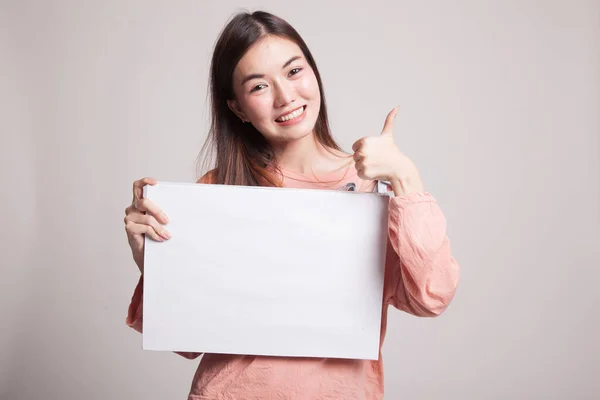 Jonge Aziatische vrouw opdagen duimen met witte leeg bord. — Stockfoto