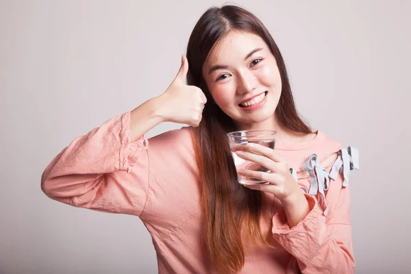 Giovane donna asiatica pollice in su con un bicchiere di acqua potabile . — Foto Stock