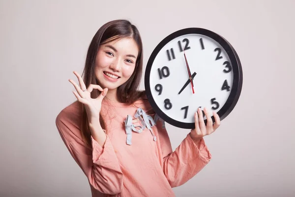 Ung asiatisk kvinna show Ok med en klocka. — Stockfoto