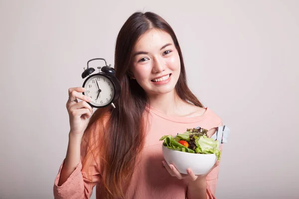 Ung asiatisk kvinna med klocka och sallad. — Stockfoto